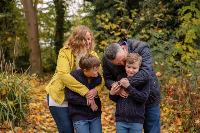 Claire and her husband cuddling their boys in an autumn park