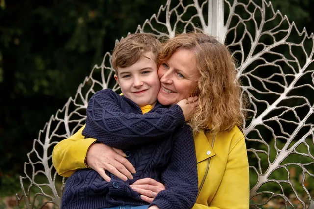 Claire cuddling one of her boys beside an autumn garden chair