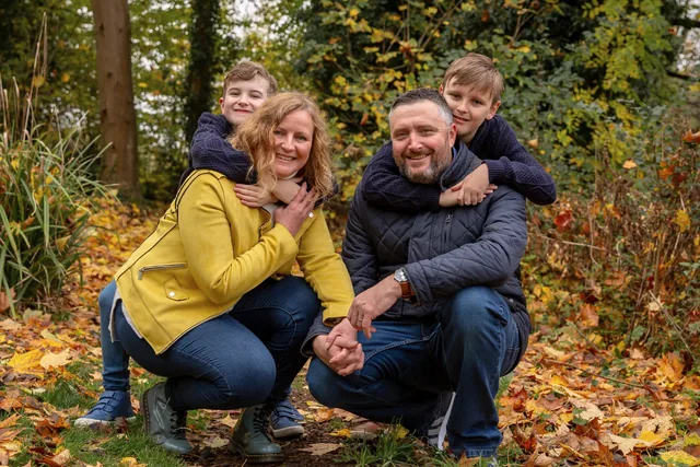 Claire and her husband giving their boys piggybacks in an autumn park