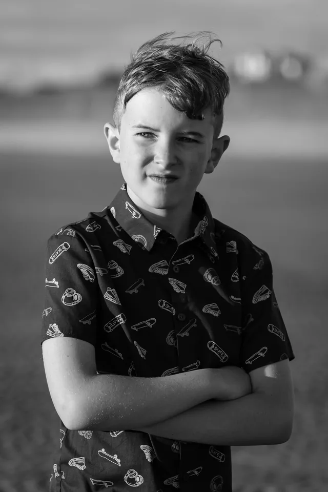 Black and white beach portrait of one of Claire’s boys with his arms folded