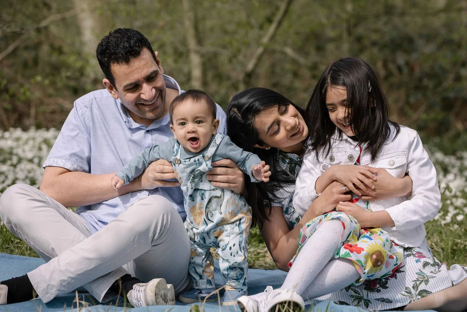 A family sitting together among bluebells in a wood