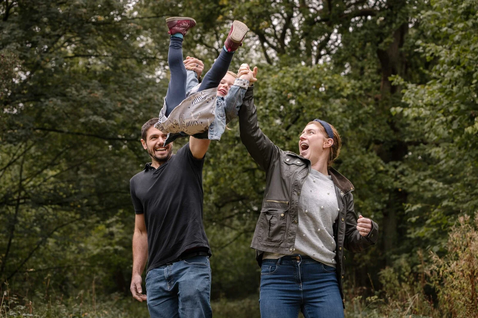 Parents playing with their child during a woodland walk