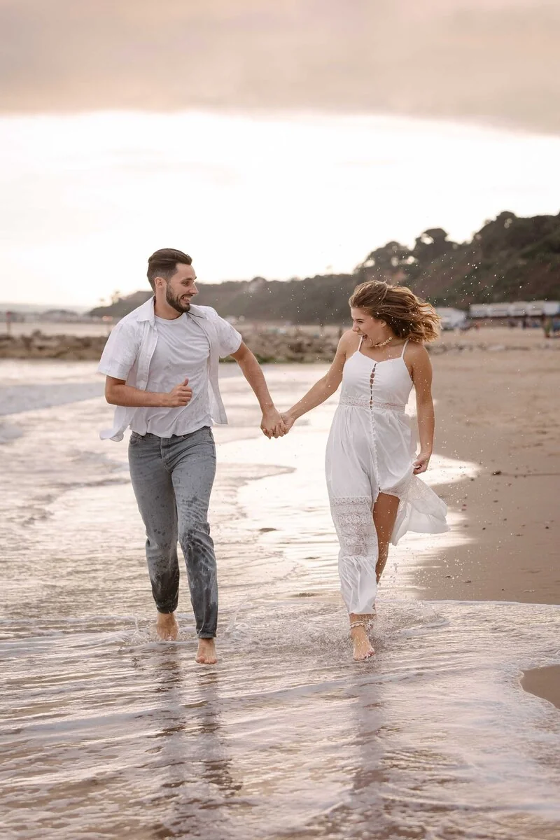 A couple holding hands and running through shallow seawater